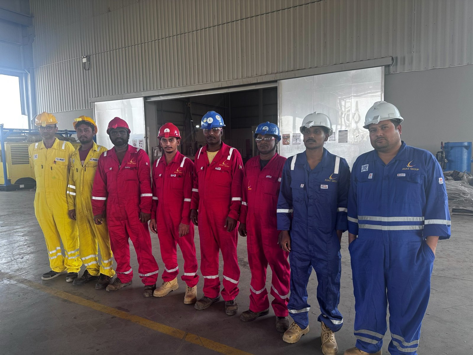 A group of men in overalls and helmets standing in a line AI-generated content may be incorrect.